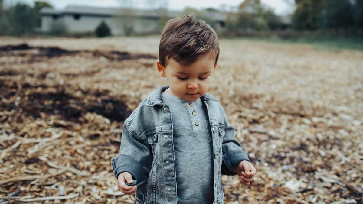 Criança com jaqueta jeans brincando na rua