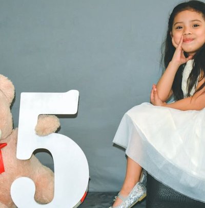 menina com vestido branco com ursinho do lado